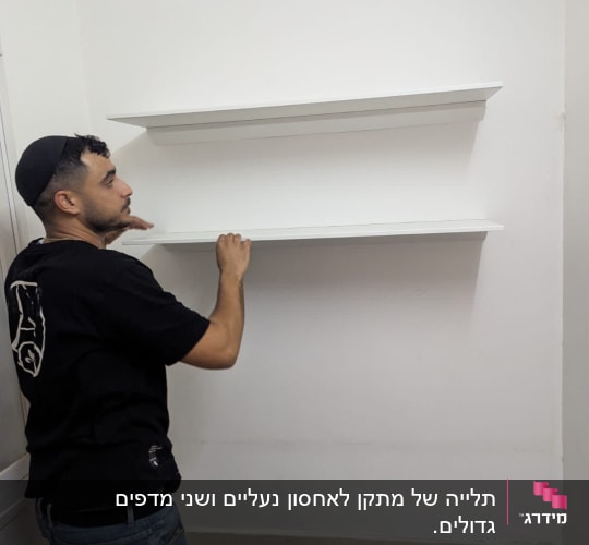 אדם מתקין מדפים לבנים על קיר לבן